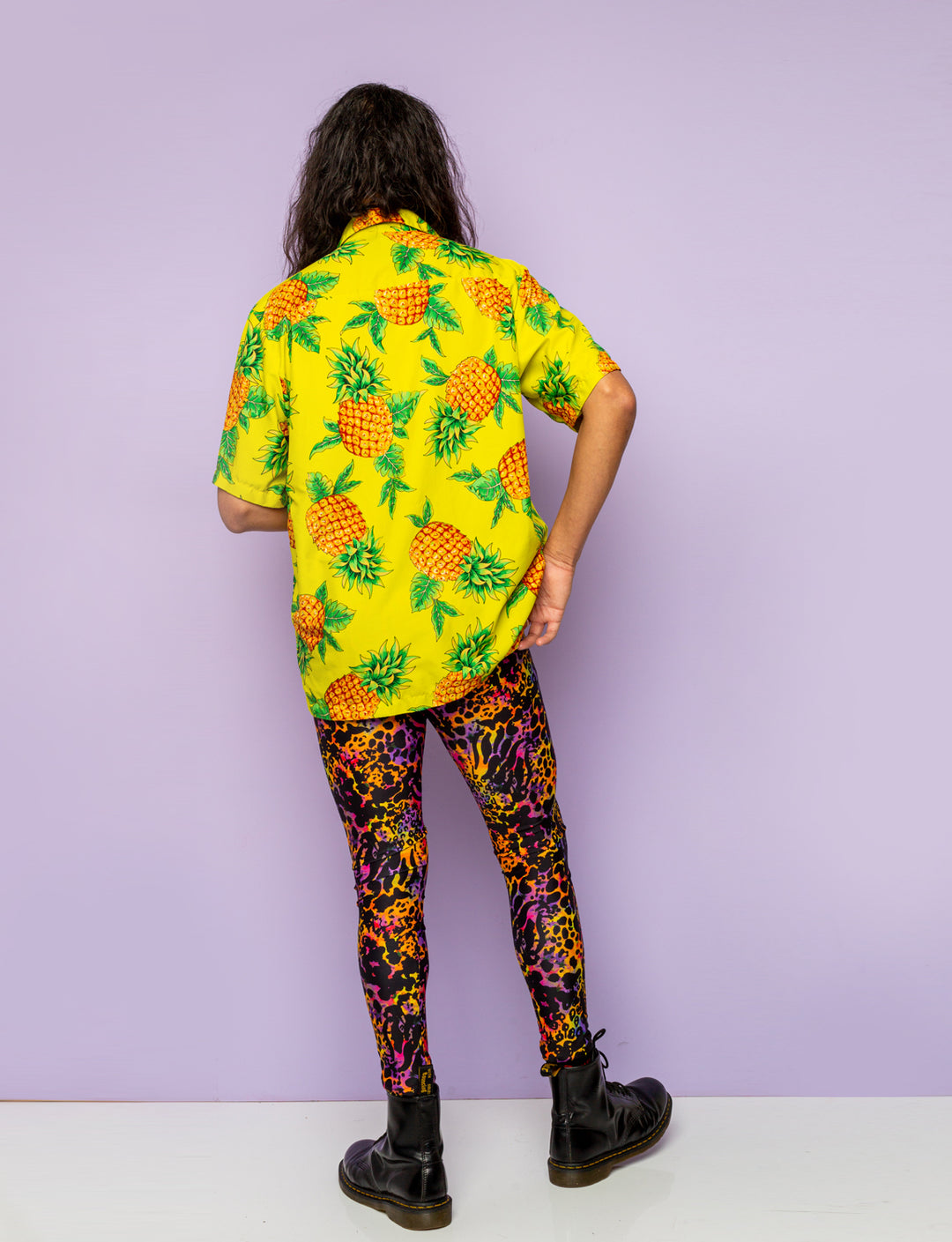 Back view of a man modelling a pair of purple leopard print leggings.