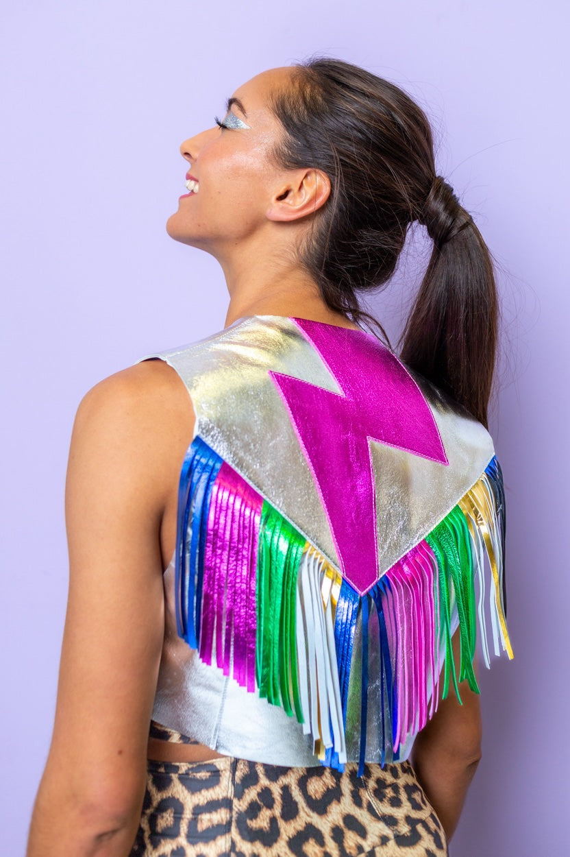 woman wearing a silver foil fringed waistcoat with rainbow fringing and a lightening bolt motif on the back.