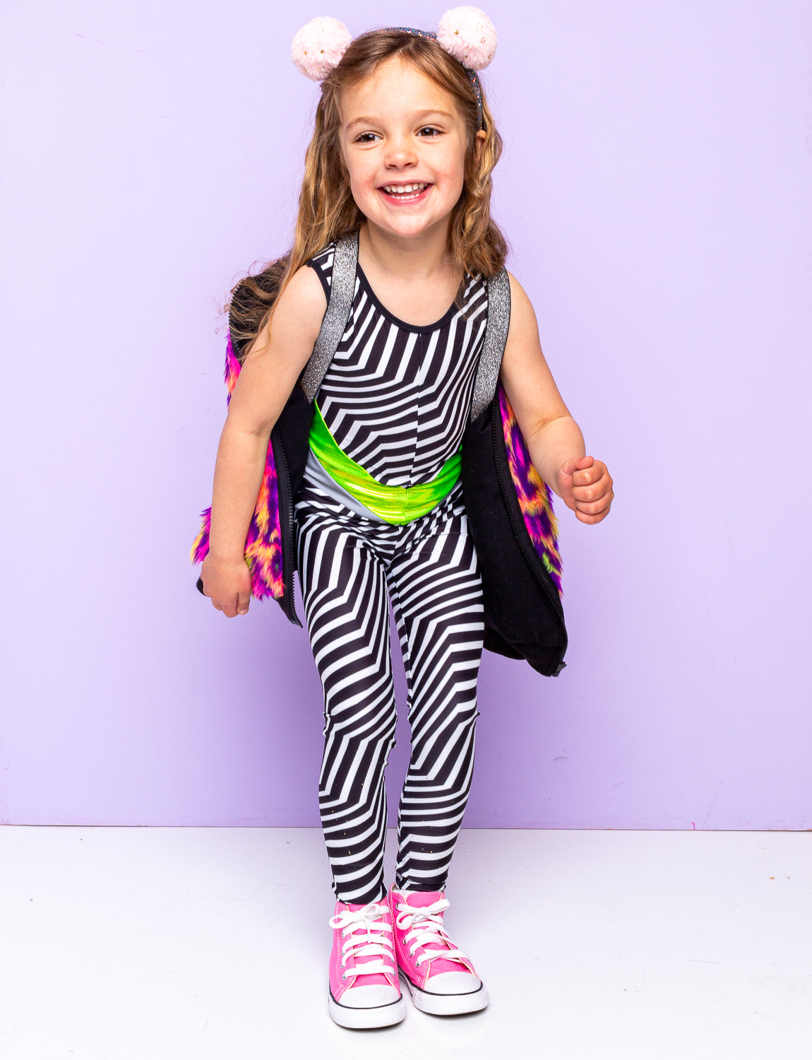 Girl wearing a black and white striped catsuit with pink converse trainers.