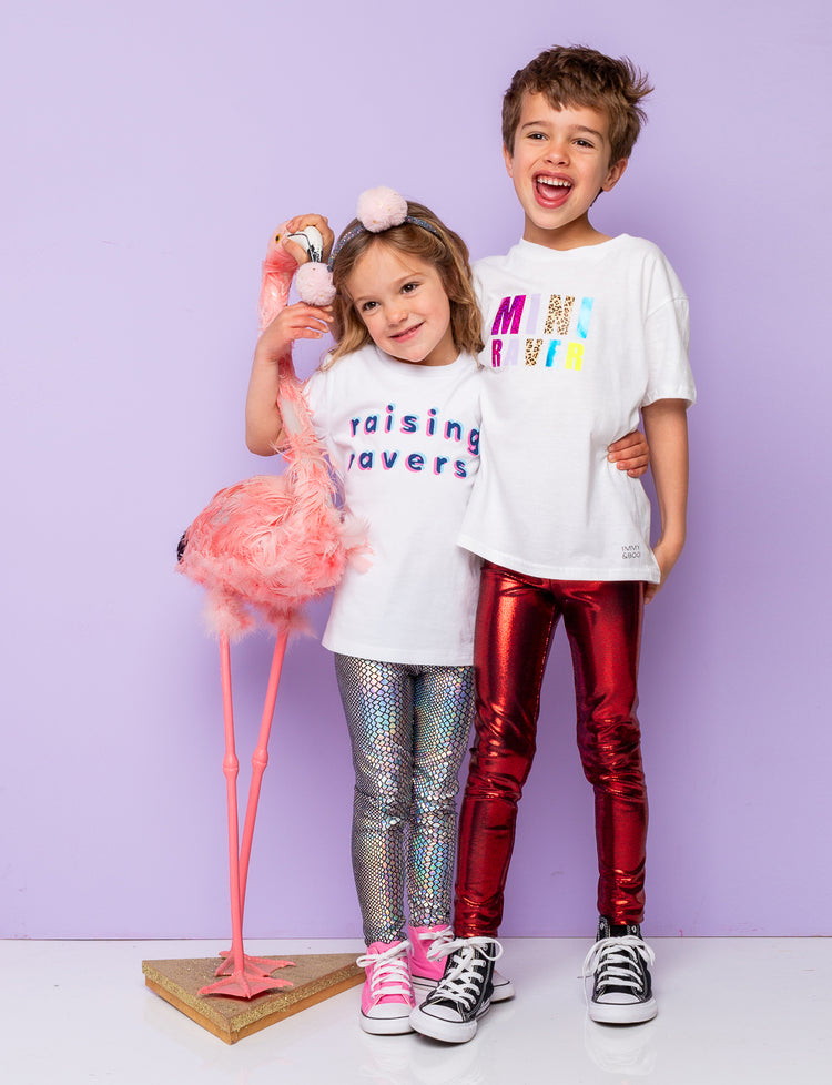 Boy and girl modelling shiny leggings and white t-shirts holding a model flamingo.