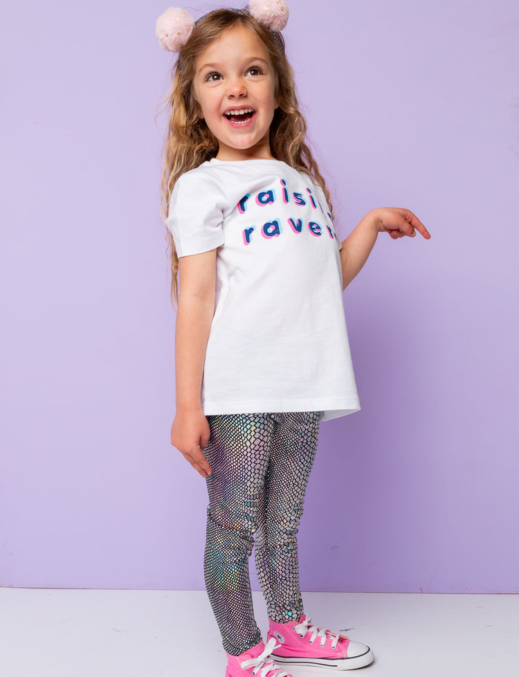 Girl wearing silver holographic snakeskin lycra leggings with a white t-shirt that says 'raising ravers'.
