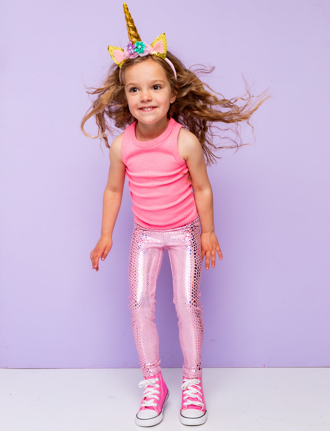 Girl wearing pink holographic snakeskin leggings with a pink vest top and unicorn headband.