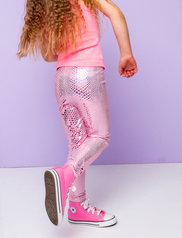 Girl wearing pink holographic snakeskin leggings with a pink vest top and pink converse trainers.