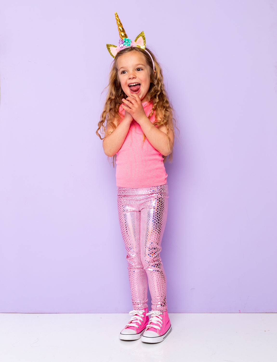 Girl wearing pink holographic snakeskin leggings with a pink vest top and unicorn headband.