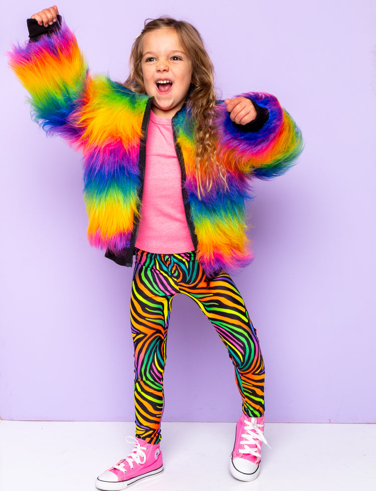 Girl modelling rainbow zebra print leggings with a rainbow fur jacket.