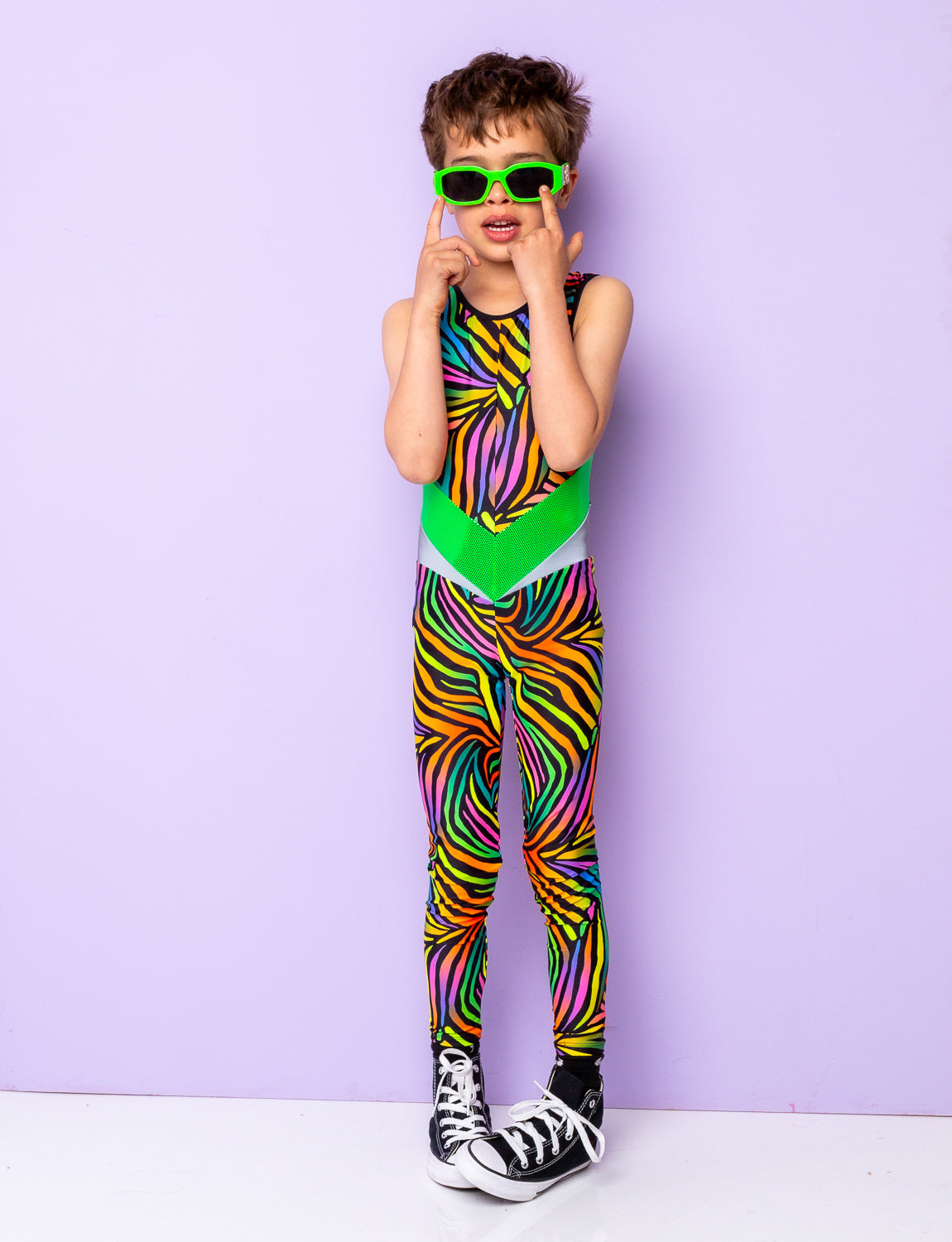 Boy modelling a multi coloured zebra print lycra catsuit and lime green sunglasses.