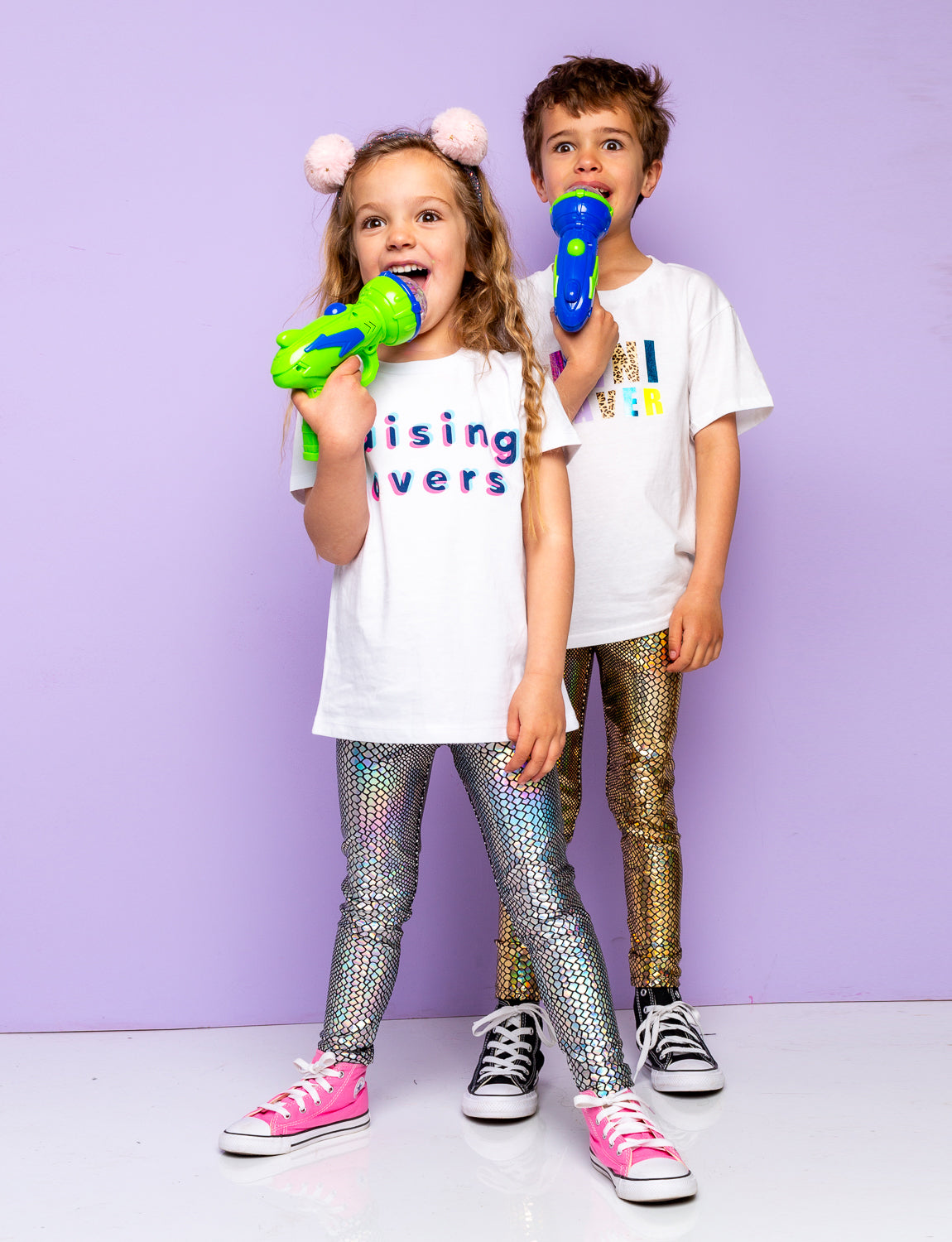 Boy and girl wearing holographic snakeskin leggings holding plastic light up guns.