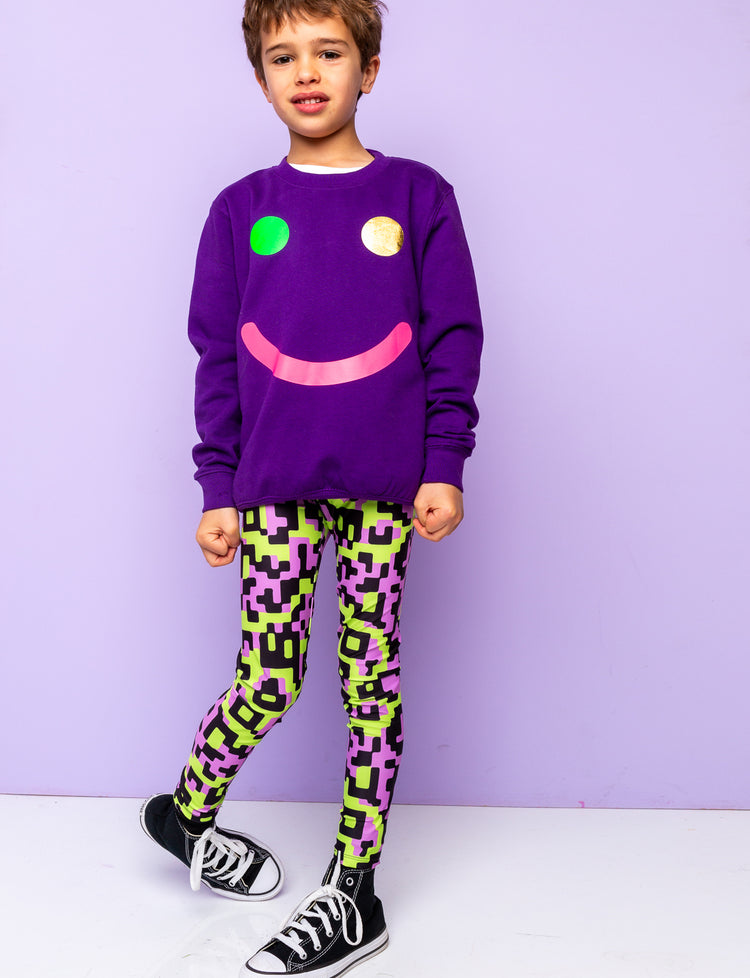 boy wearing a smily face sweatshirt and funky festival leggings