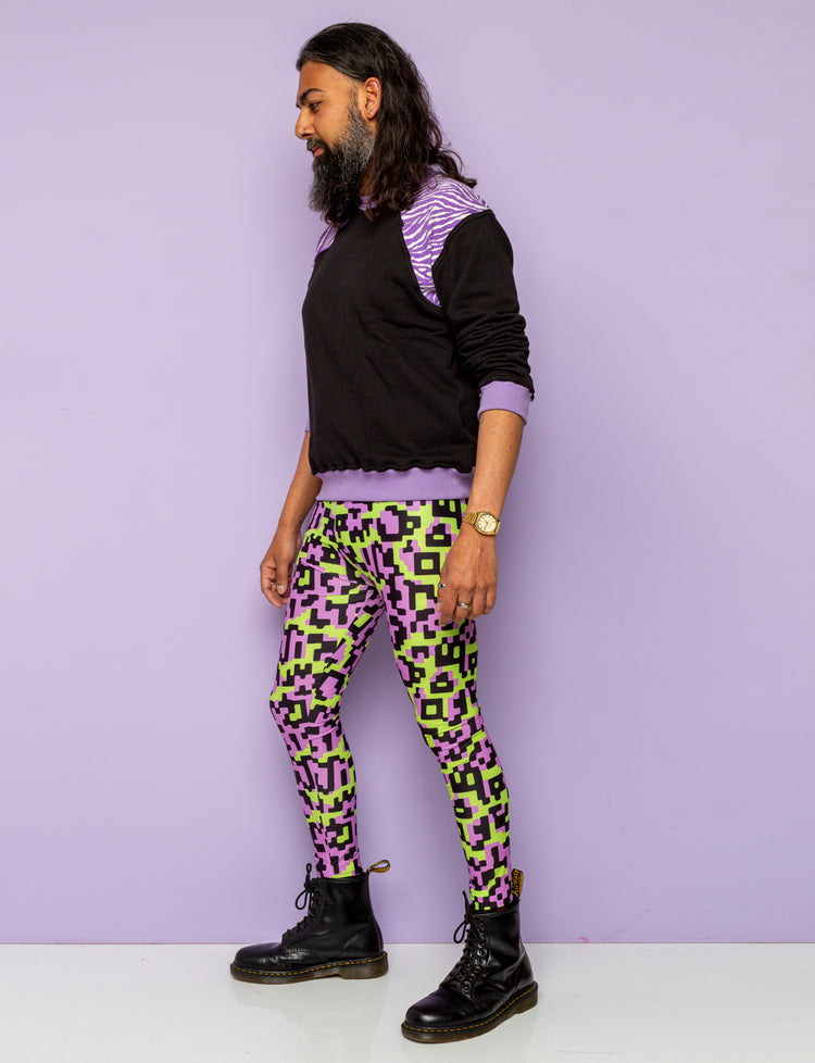 Side view of a man wearing funky festival leggings with a black and purple zebra print sweatshirt.