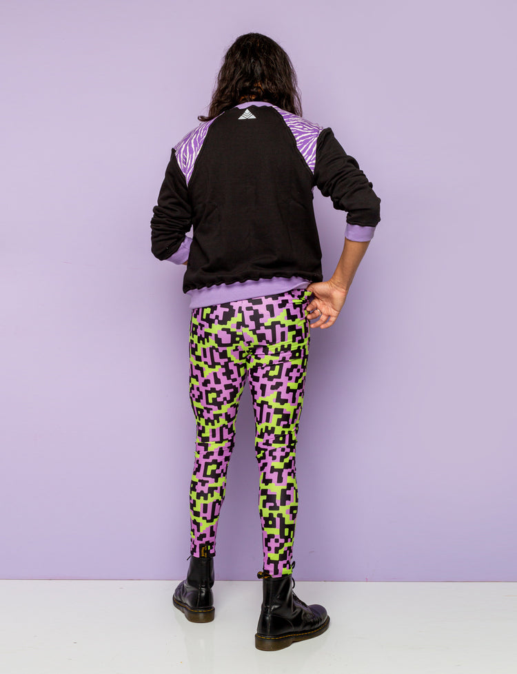 Back view of a man wearing funky festival leggings with a black and purple zebra print sweatshirt.