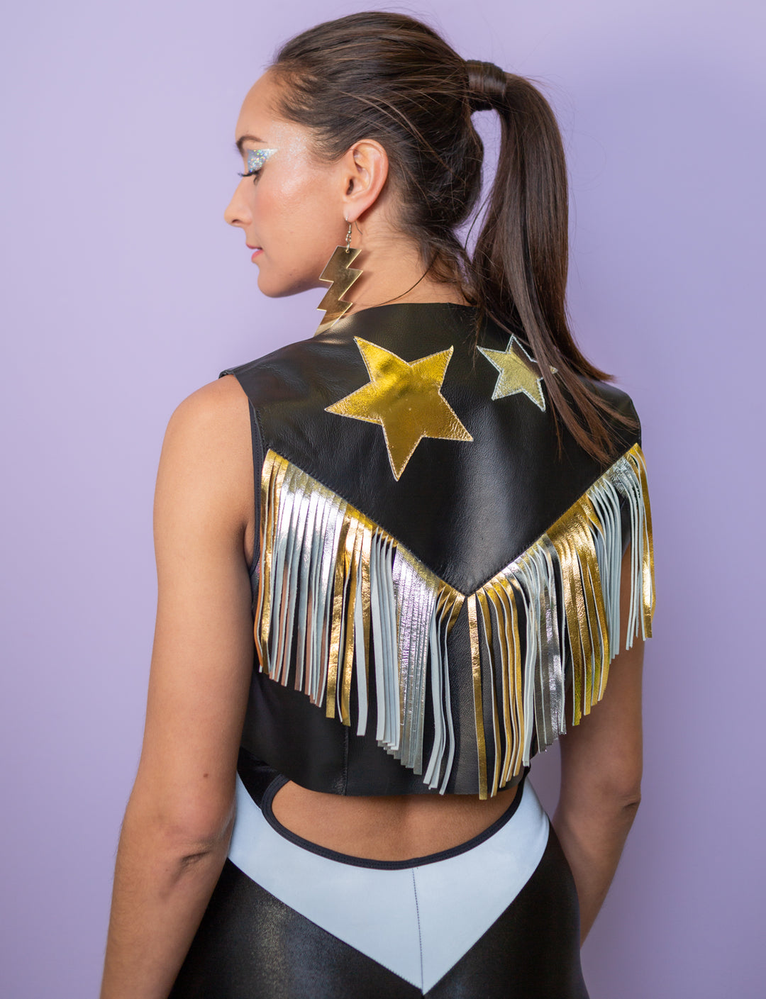 Woman wearing a black leather waistcoat with gold and silver tassels and appliqued stars