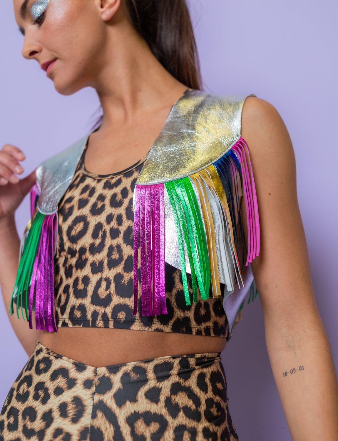 woman wears a silver and multi coloured fringed leather waistcoat and leopard print two piece