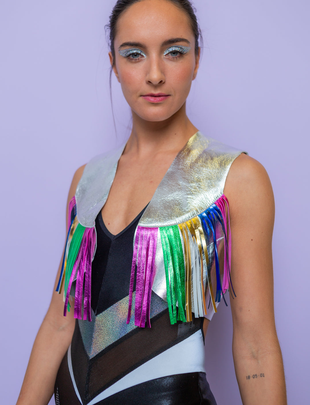 Woman wearing a silver leather jacket with multi coloured fringing and a black lycra catsuit