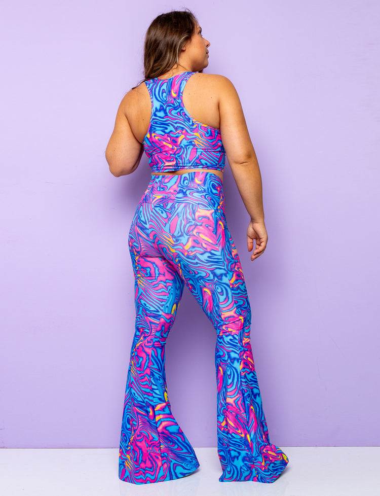 Back view of a woman modelling lycra patterned flares with a swirly pink and blue print with a matching crop top.