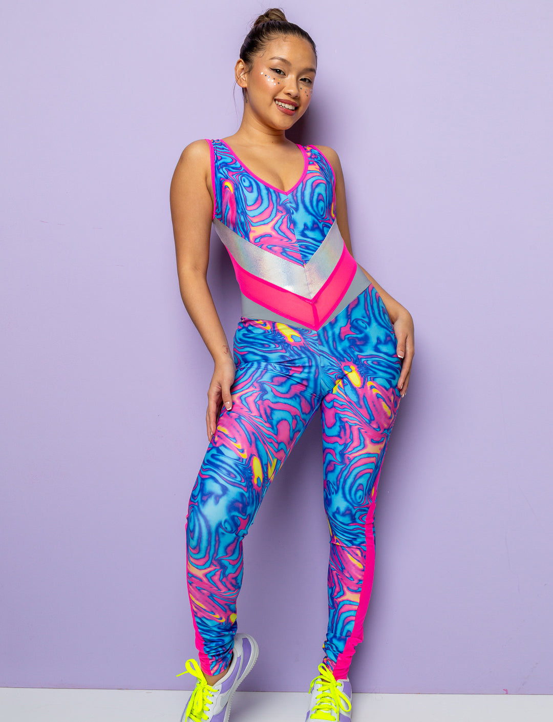 Model wearing a swirly pink and blue patterned lycra catsuit with mesh panels.