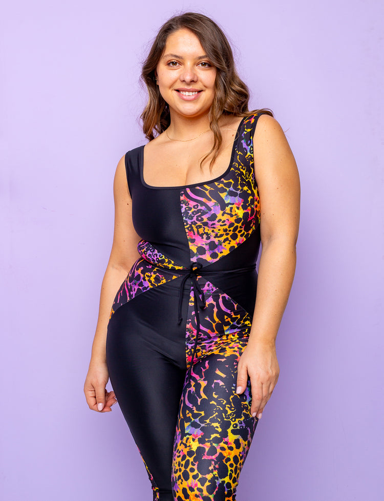 Woman modelling a purple leopard print catsuit with contrasting black panels.