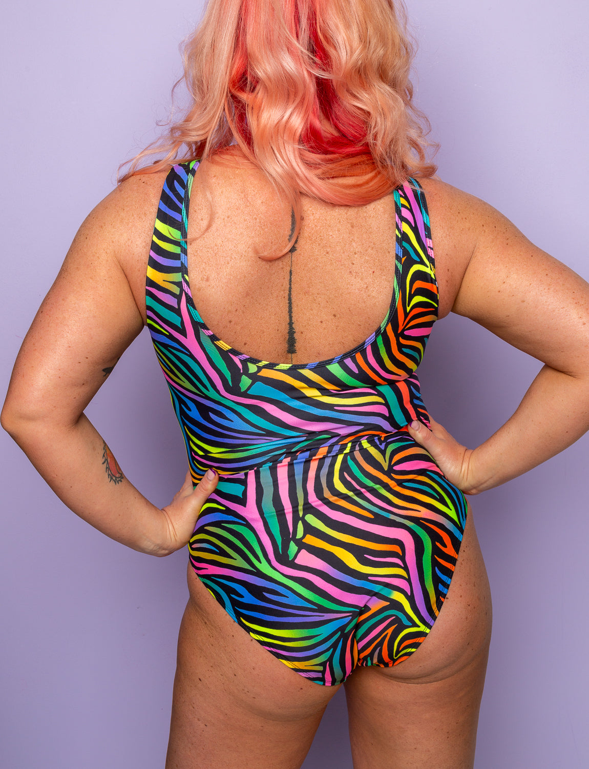 Back view of a woman wearing a rainbow zebra print swimsuit.