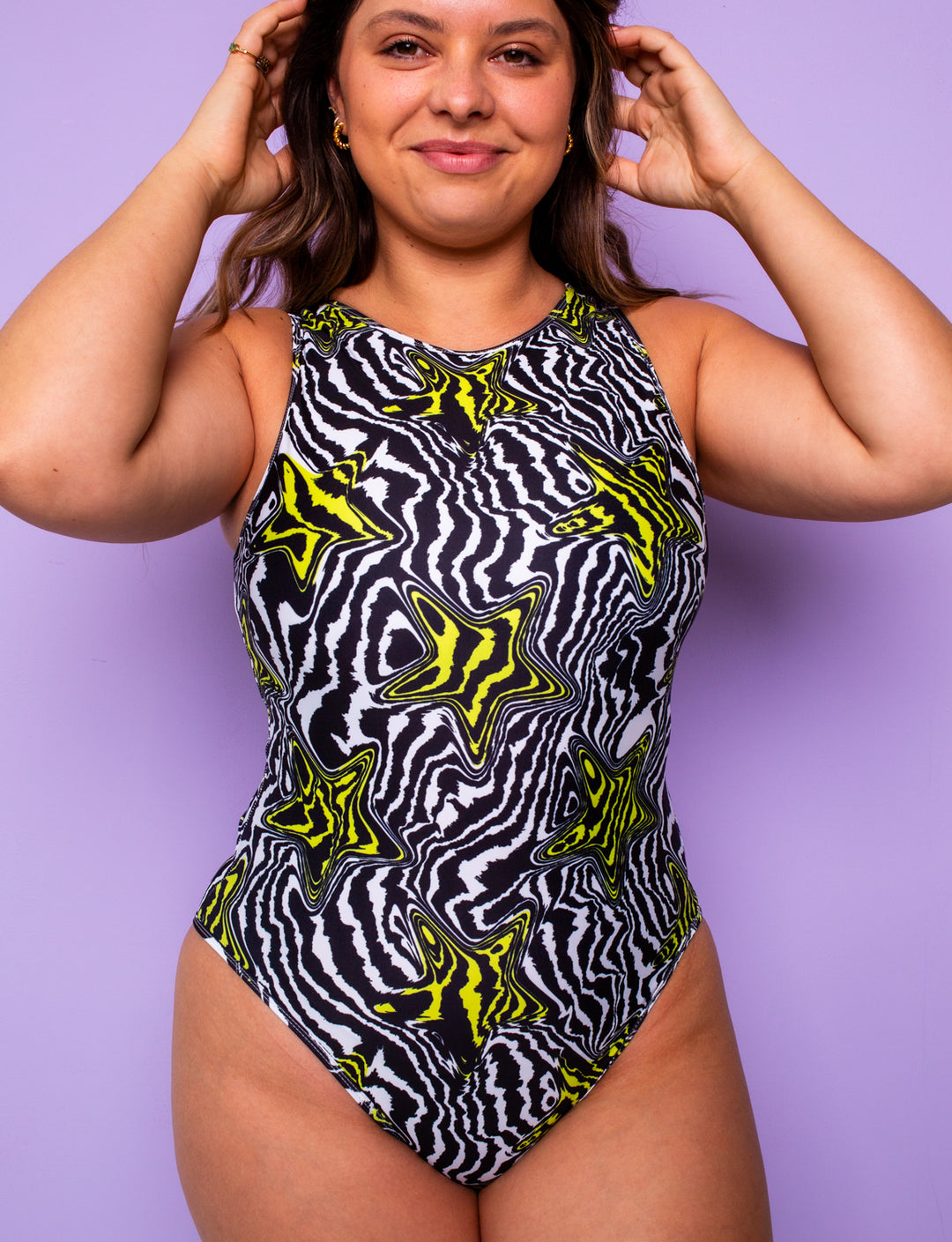 Woman wearing a high leg bodysuit with a black and white zebra print and yellow stars.