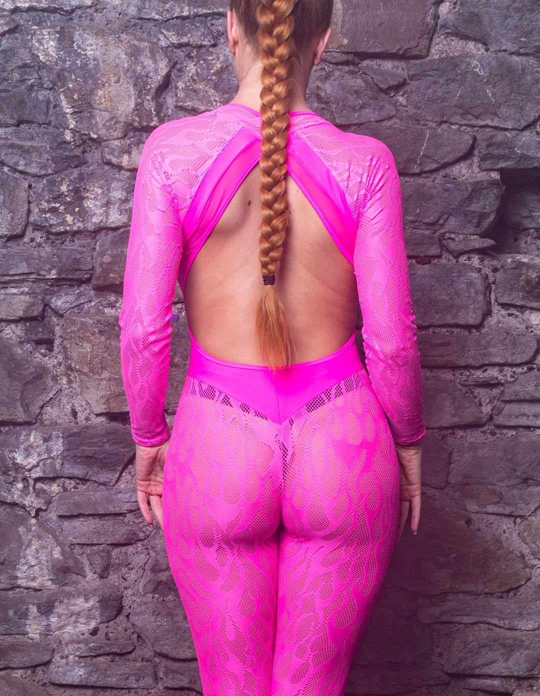 back view of lady wearing a backless, neon pink flame mesh lace catsuit with sleeves