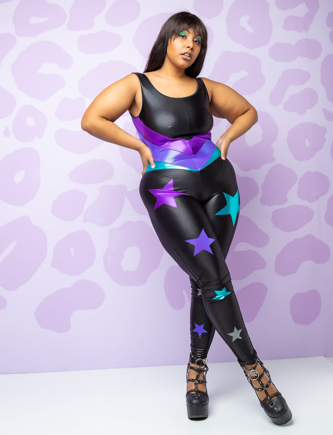 woman wearing black catsuit with purple and turquoise stars on the legs and panels on the body