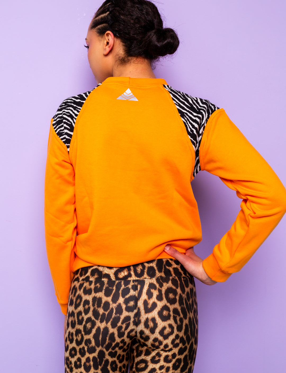 back of woman wearing orange sweatshirt with zebra print shoulders and leopard print leggings