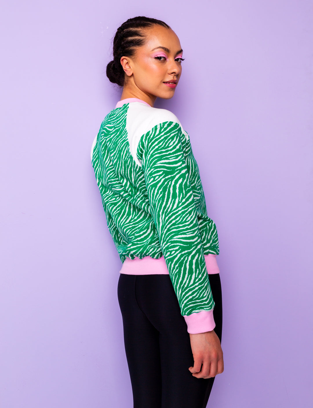 side view of a woman wearing a green zebra print sweatshirt with pink cuffs