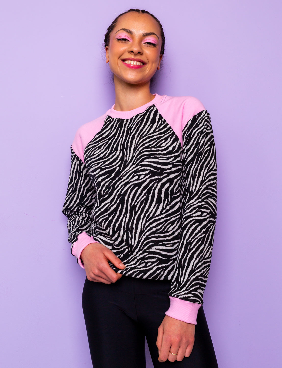 woman wearing a black and white zebra print sweatshirt with pink panels tucked under at the hips