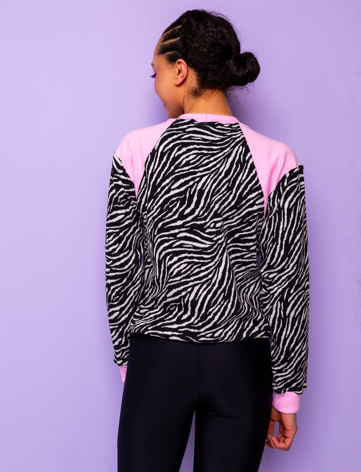 back view of a woman wearing a black and white zebra print sweatshirt with pink panels tucked under at the hips
