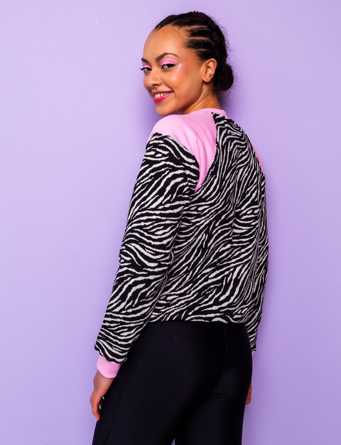side view of a woman wearing a black and white zebra print sweatshirt with pink panels tucked under at the hips