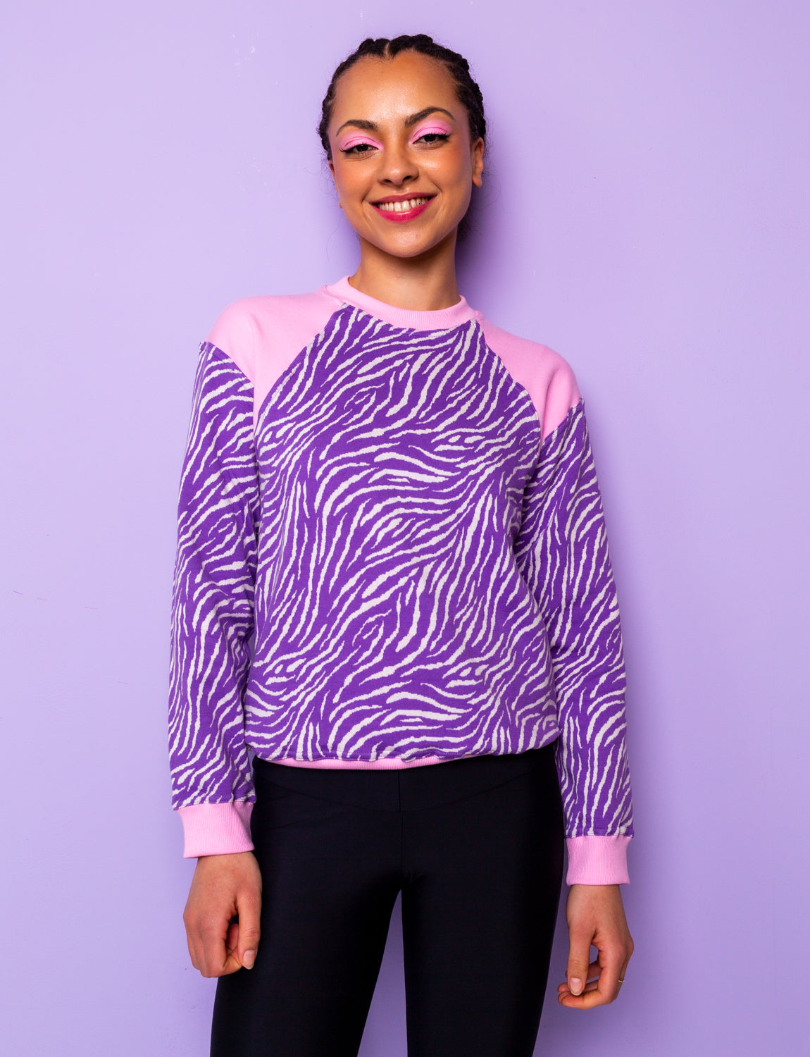 woman wearing a purple zebra print sweatshirt with pink shoulders tucked in at the hips