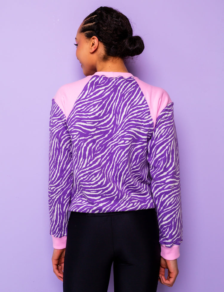 back view of a woman wearing a purple zebra print sweatshirt with pink shoulders 