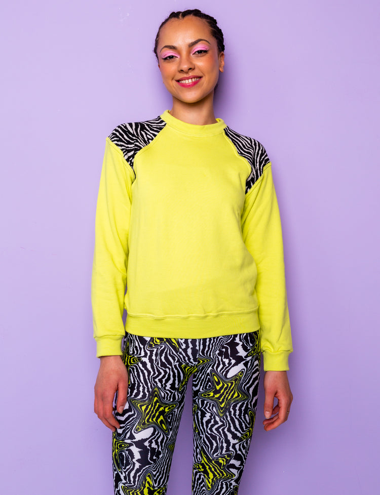 woman wearing a lime green sweatshirt with black and white zebra print shoulders