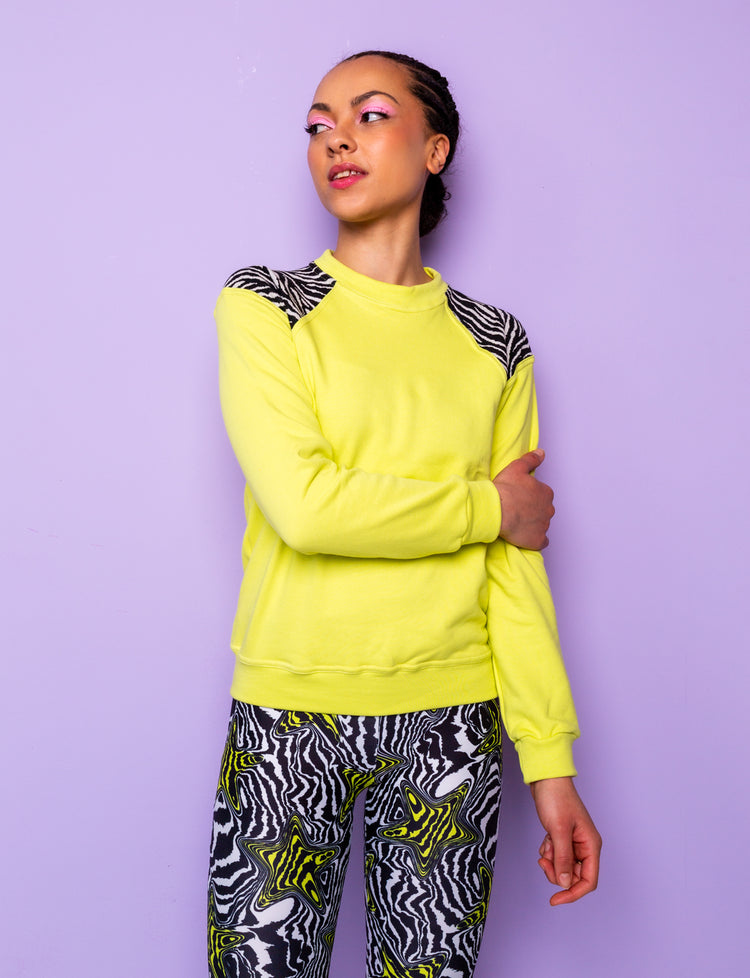 woman wearing a lime green sweatshirt with black and white zebra print shoulders and star patterned leggings