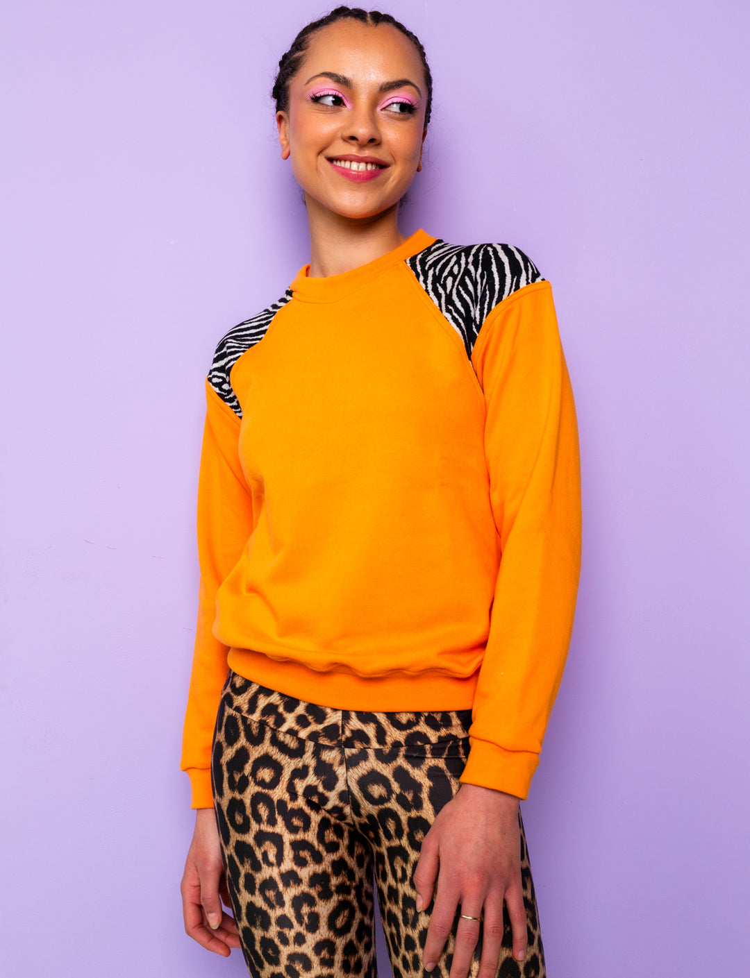 woman wearing orange sweatshirt with zebra print shoulders