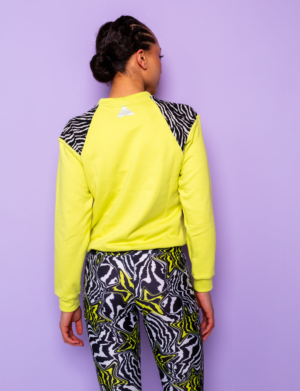 back of woman wearing a lime green sweatshirt with black and white zebra print shoulders