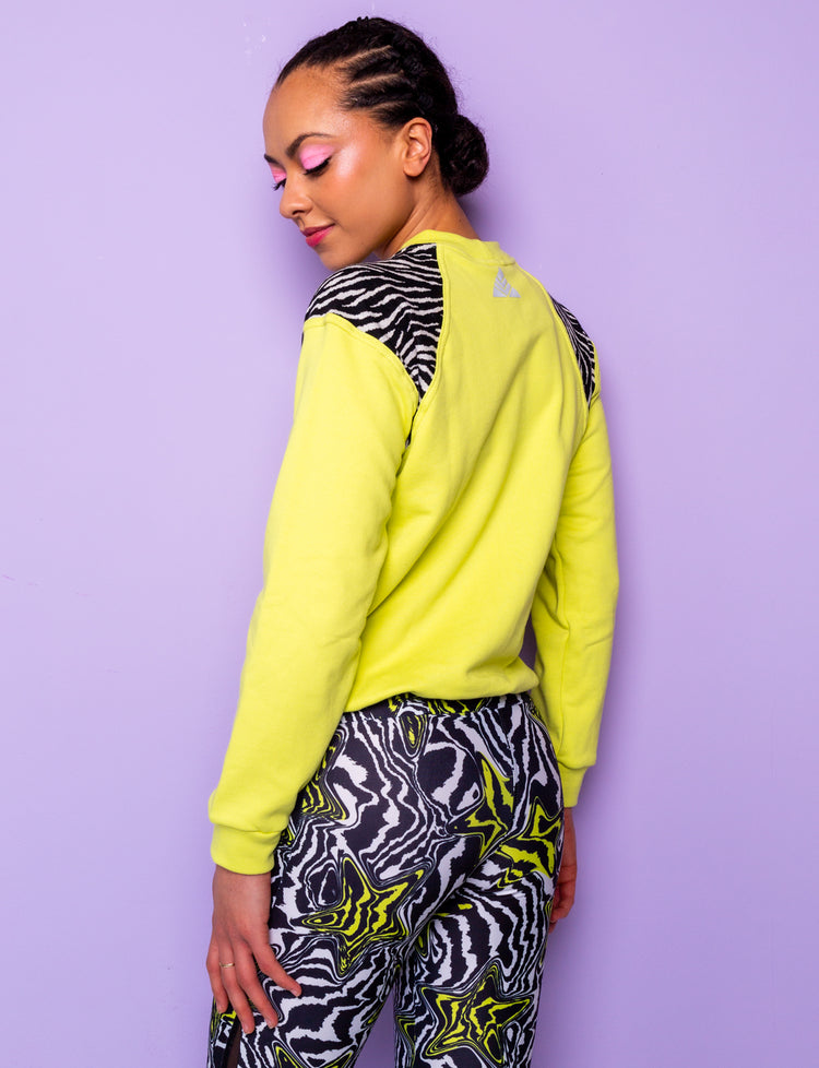 side view of woman wearing a lime green sweatshirt with black and white zebra print shoulders