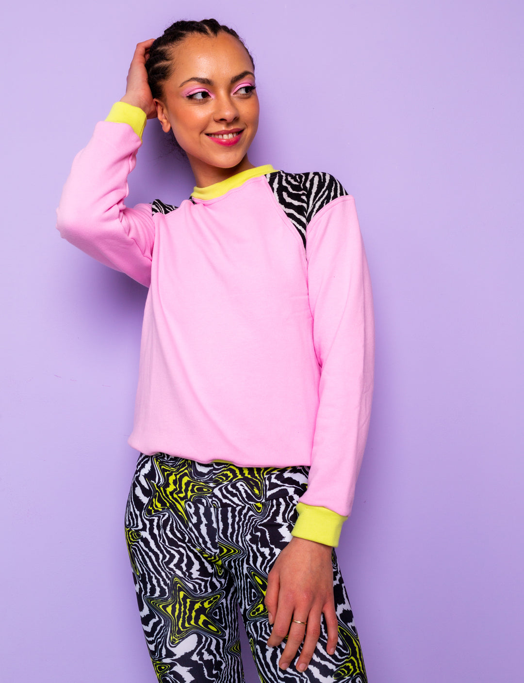 woman wearing a pink sweatshirt with zebra prints shoulders tucked in at the waist