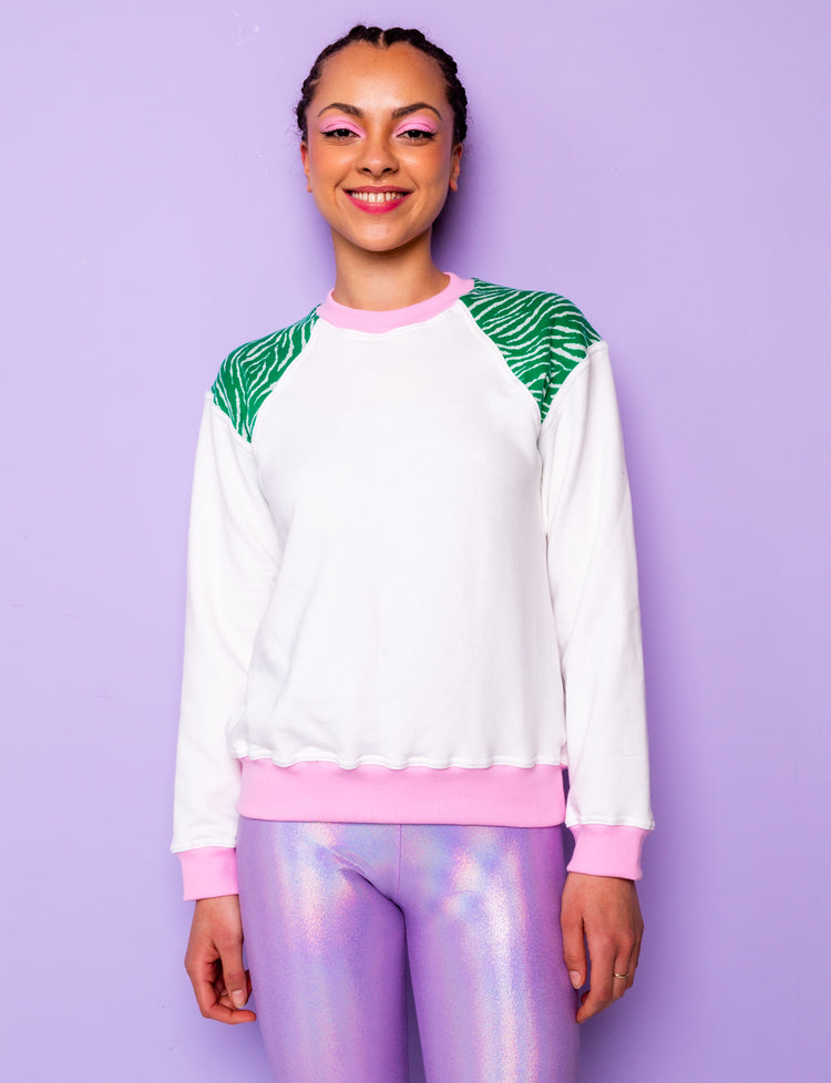 woman wearing a white sweatshirt with green zebra print shoulders and pink cuffs and waistband