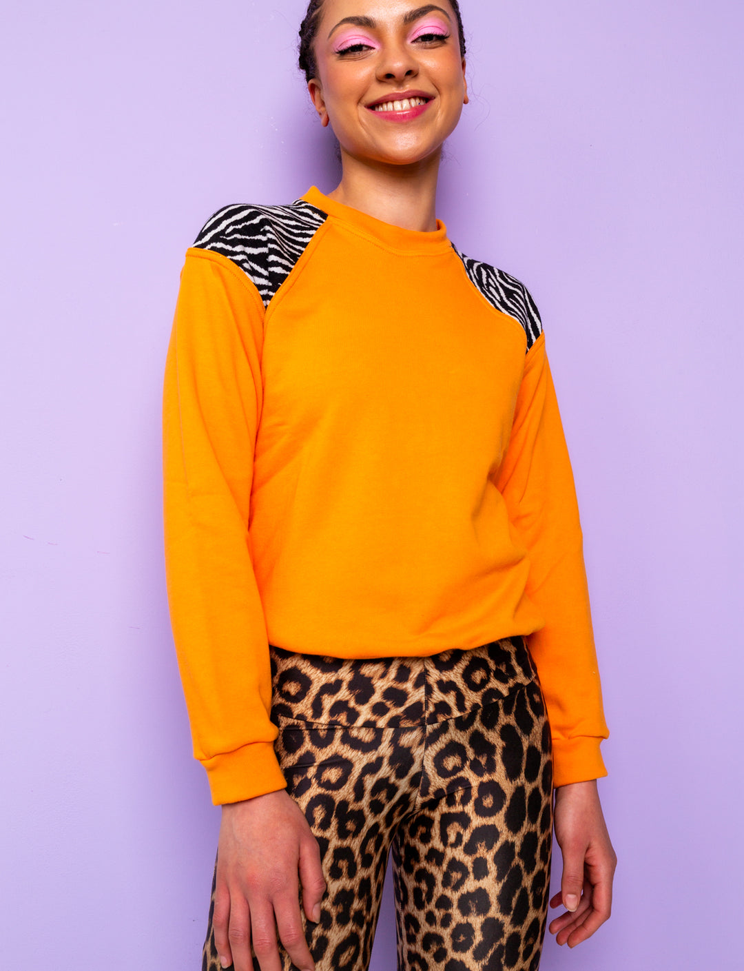woman wearing orange sweatshirt with zebra print shoulders and leopard print leggings