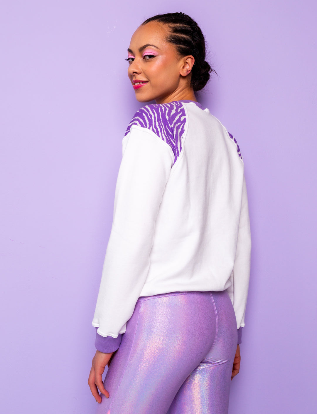 side view of woman wearing a white sweatshirt with purple zebra print shoulders