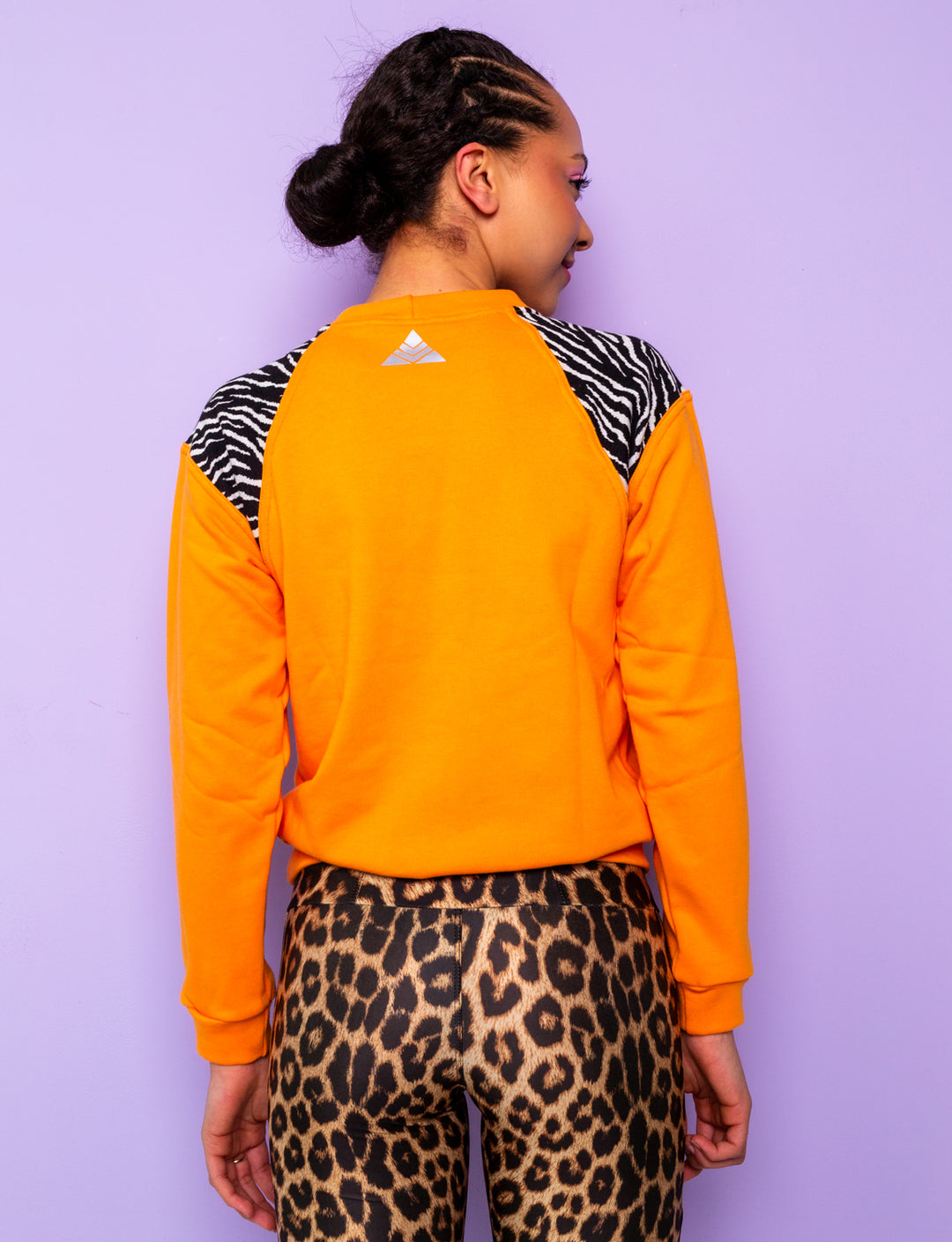 back of woman wearing orange sweatshirt with zebra print shoulders