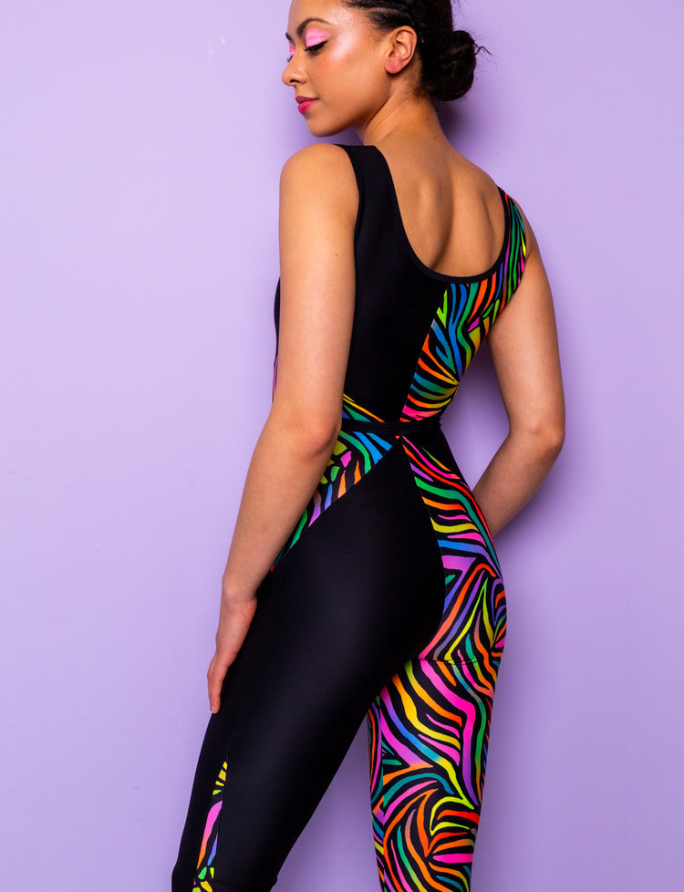 Back view of a woman wearing a printed lycra catsuit with rainbow zebra print and contrasting black panels.