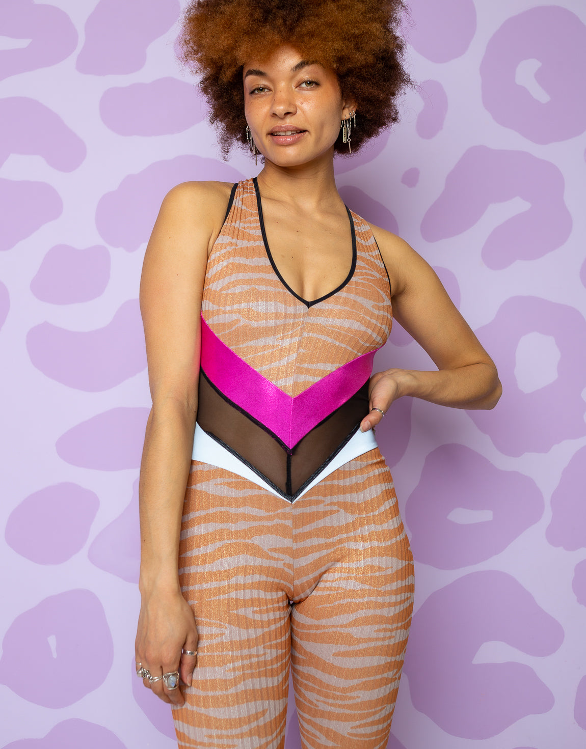 woman wearing backless flared catsuit with orange and grey zebra print and pink waistband