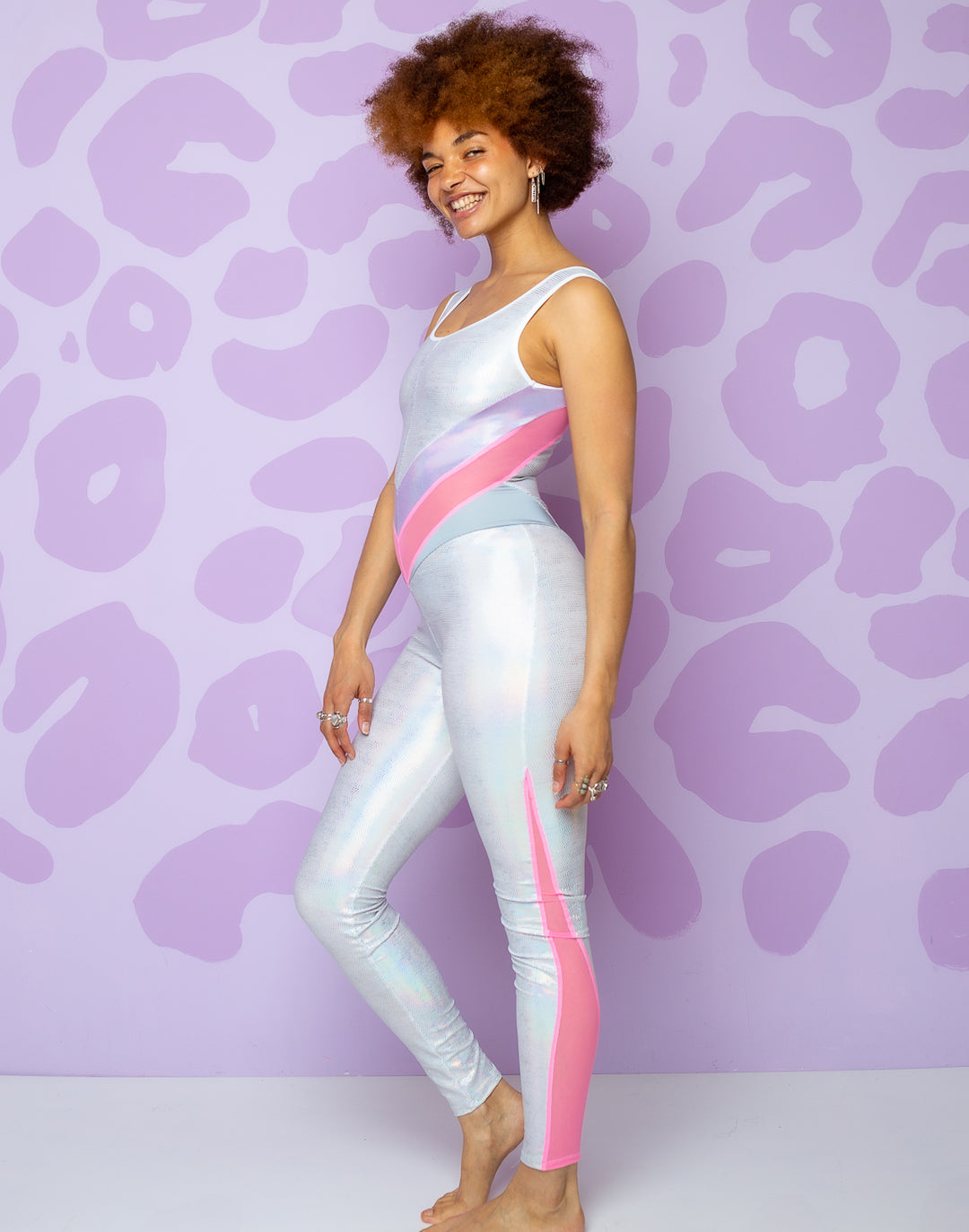 woman wearing white catsuit with lilac and pink panels in middle and pink mesh panels on side of legs