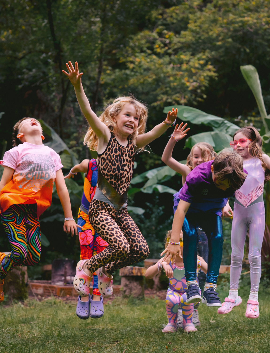 Children in colorful outfits playing outdoors with a green background