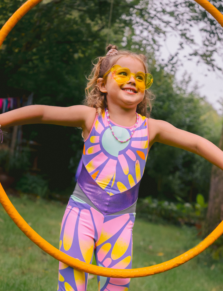 Child in colorful flower print outfit with hula hoop outdoors