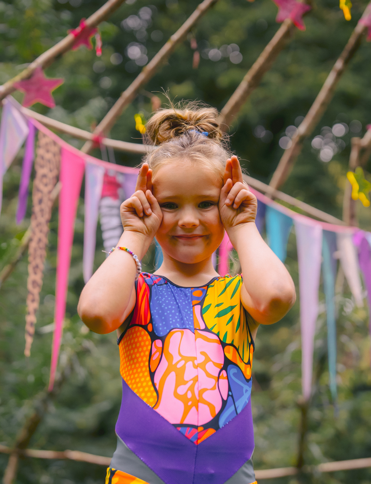 Child in a colorful swimsuit with a decorative background of flags and greenery