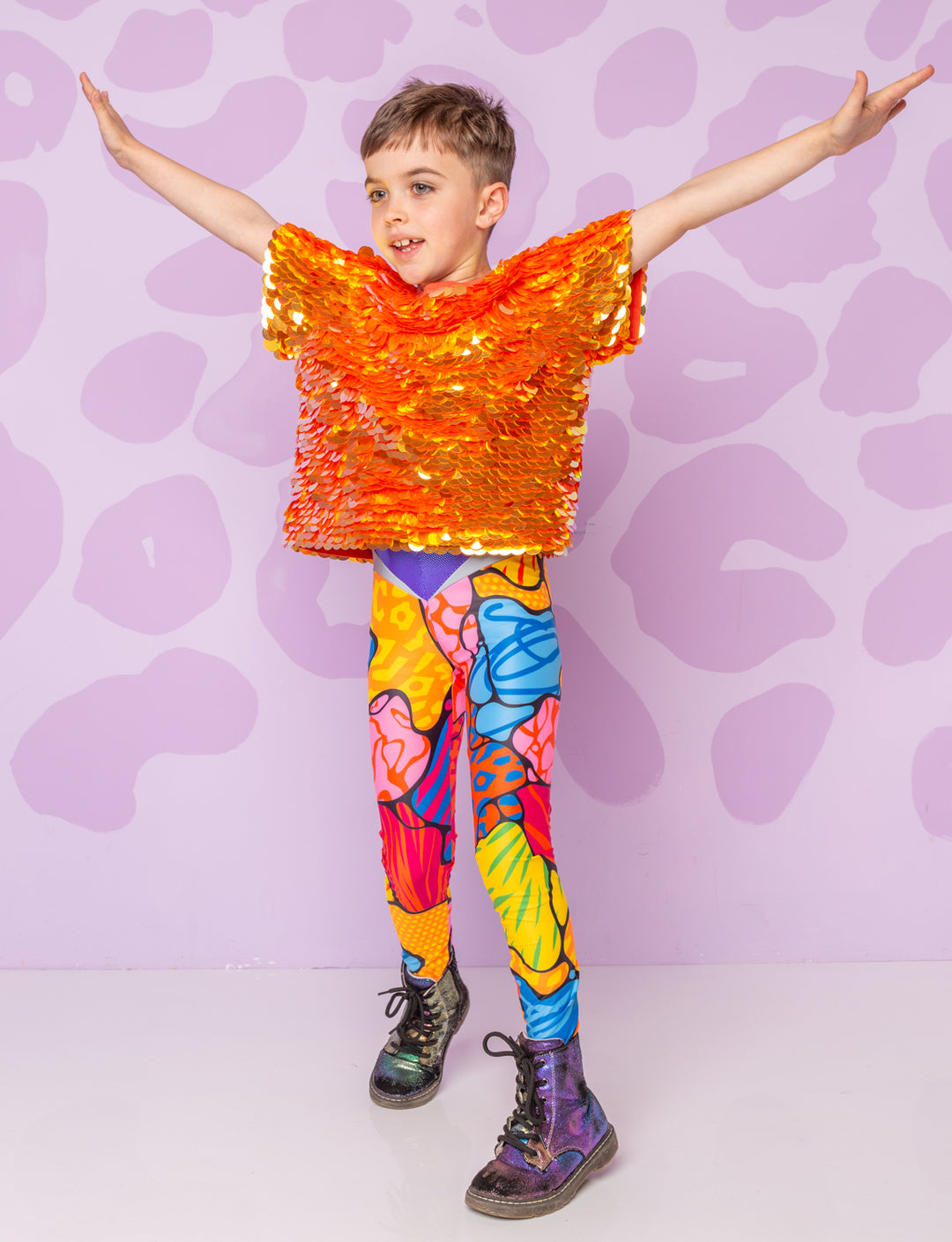 Boy wearing a patterned catsuit with a sequin top and Dr Martin boots