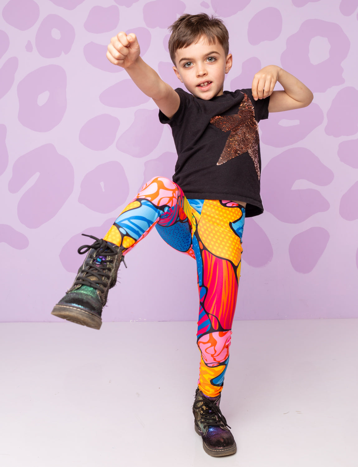 Boy kicking in the air wearing patterned leggings and star t-shirt