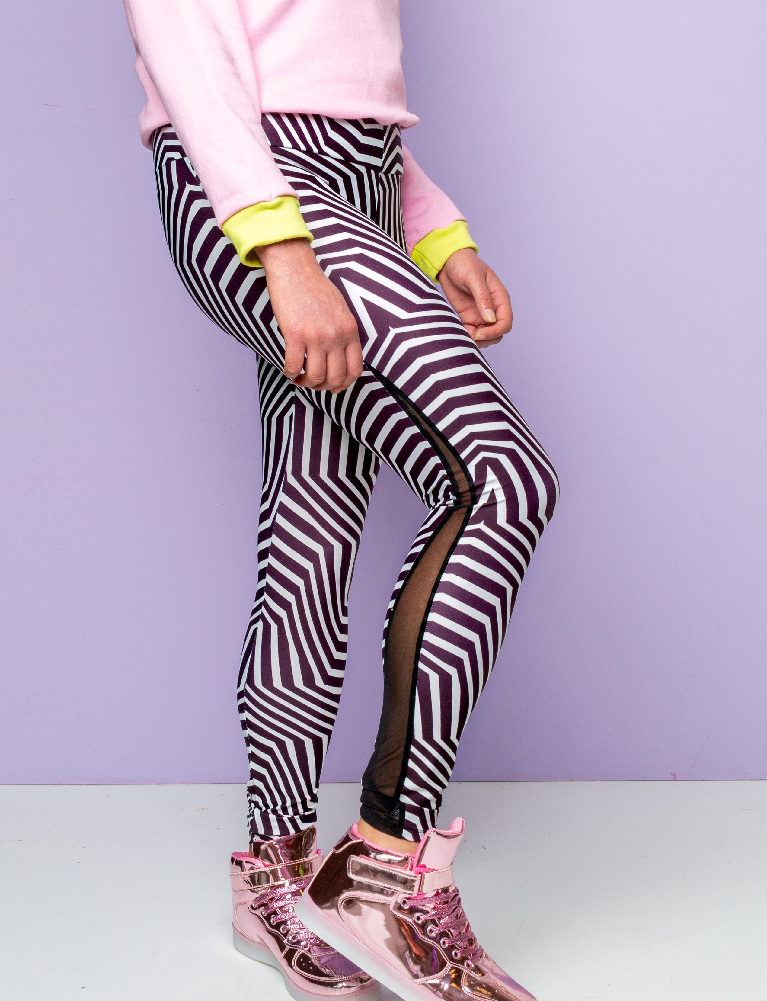 Close up of a woman wearing psychedelic black and white printed leggings with a black mesh stripe. 